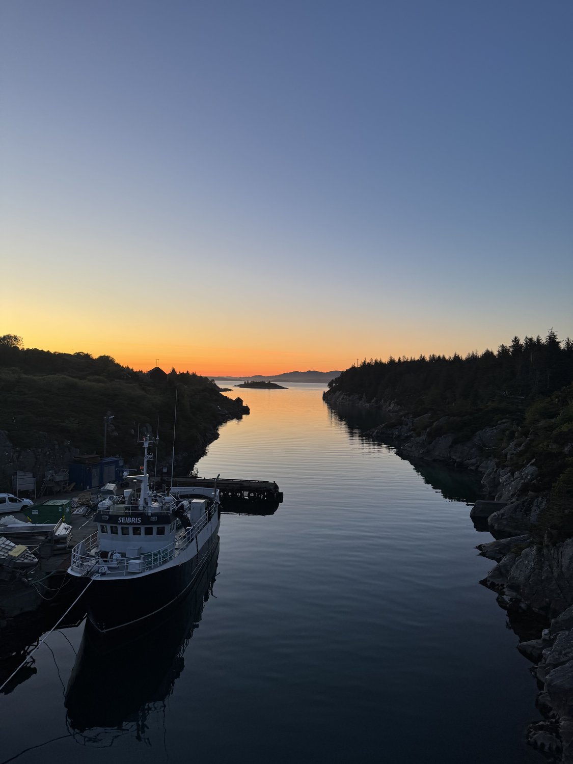 En arbeidsbåt på fjorden i solnedgang