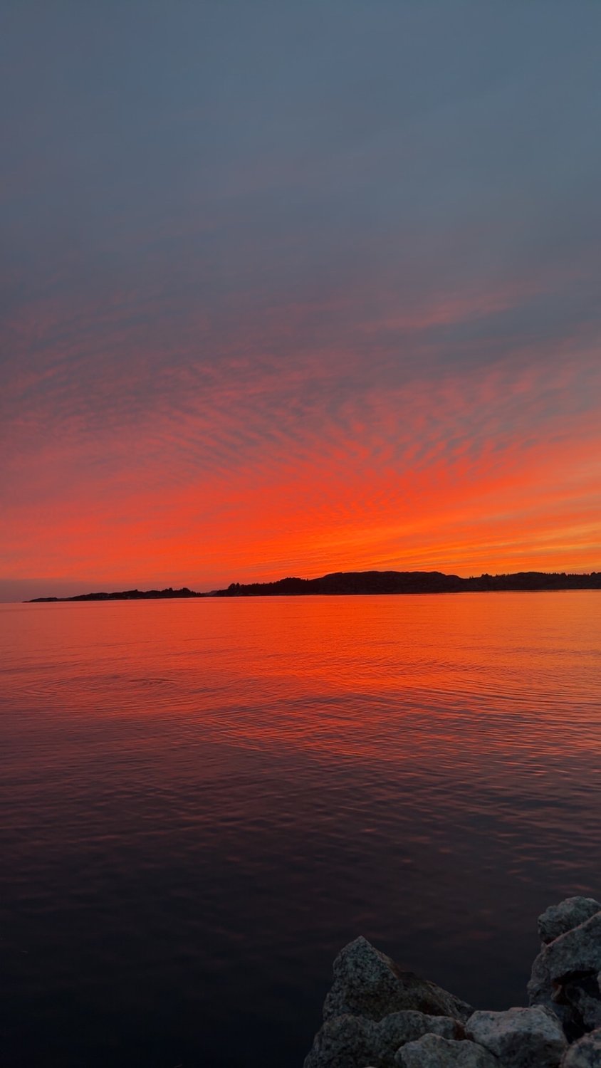 En rød solnedgang over fjorden ved Austevoll